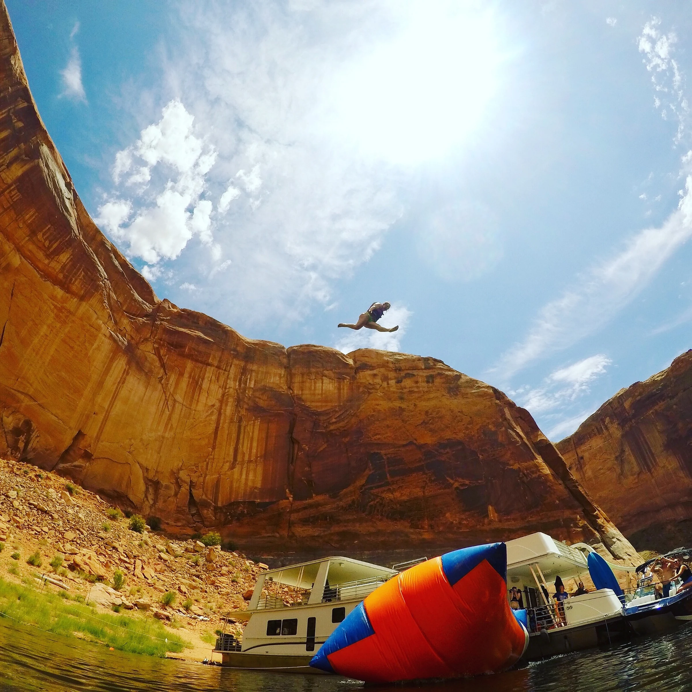 A lakeside leap beside sandstone cliffs and a houseboat
