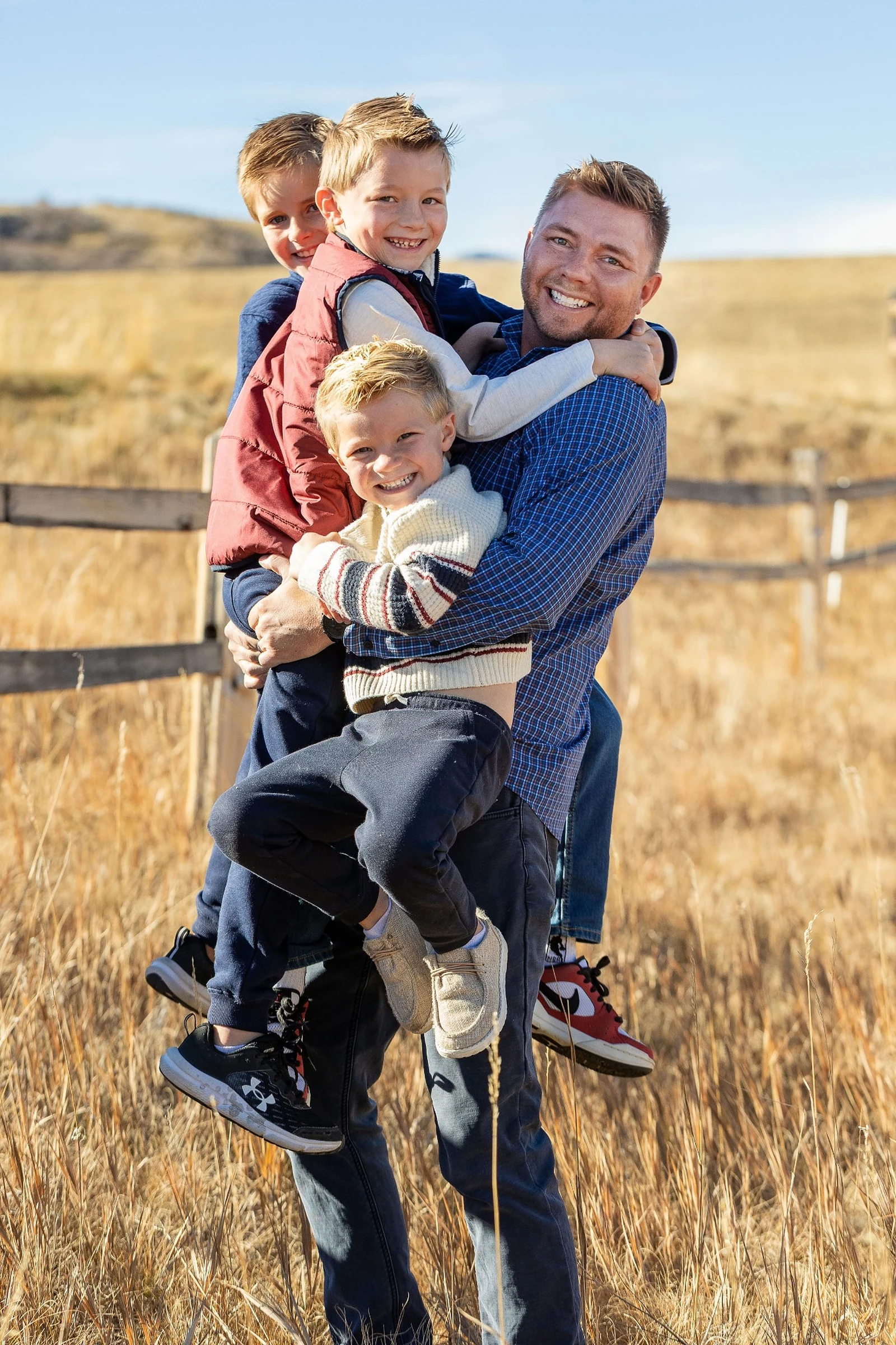 Dane holding his three boys outdoors